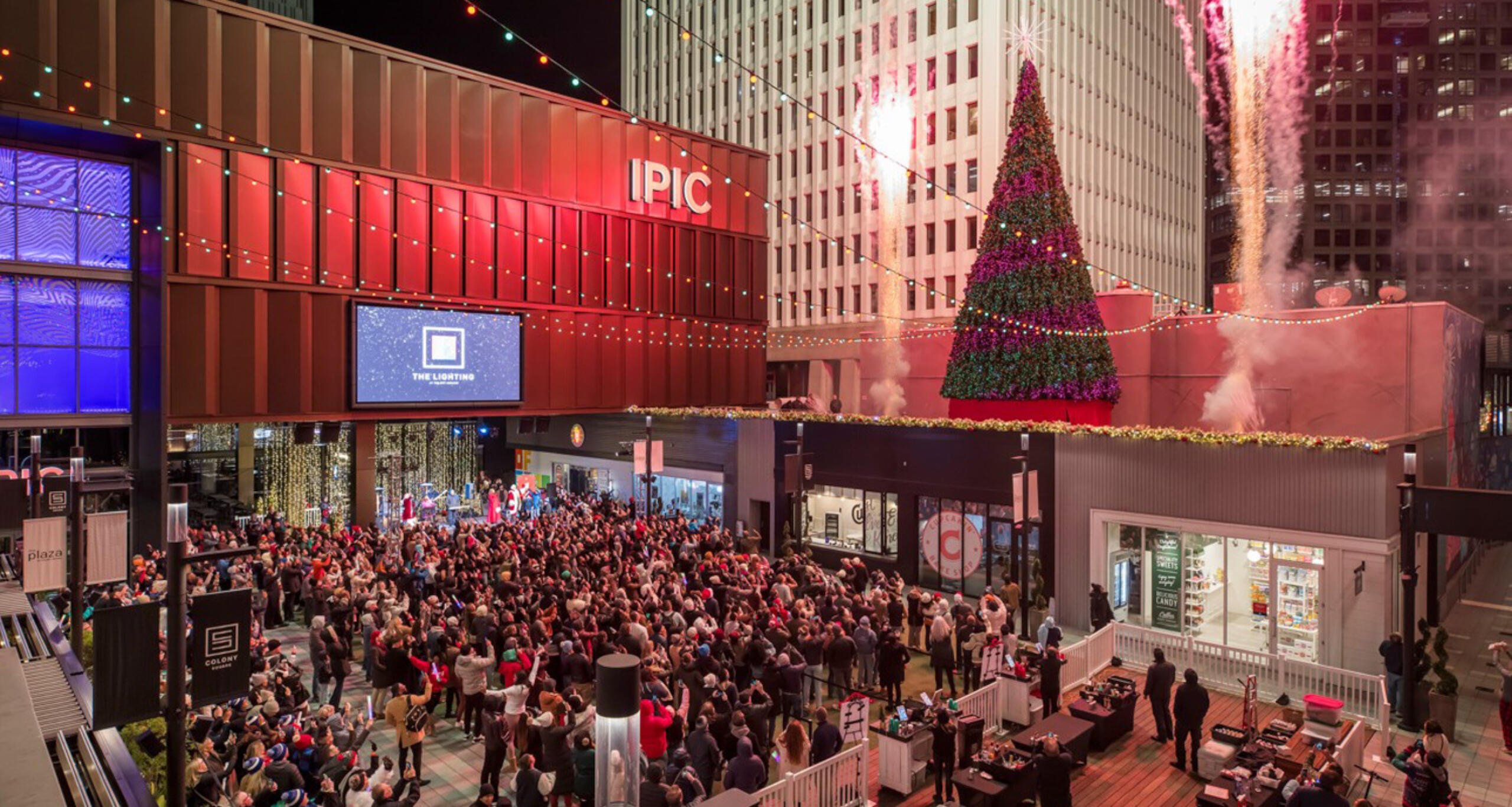 A crowd of people watching the tree lighting and fireworks at Colony Square