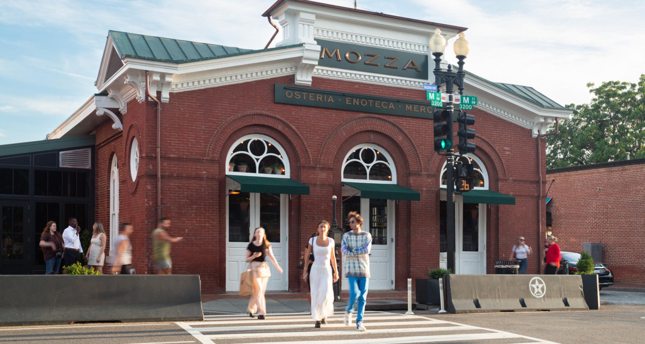 Visitor walking on a sidewalk and crossing the street in front of Mozza at Georgetown Park