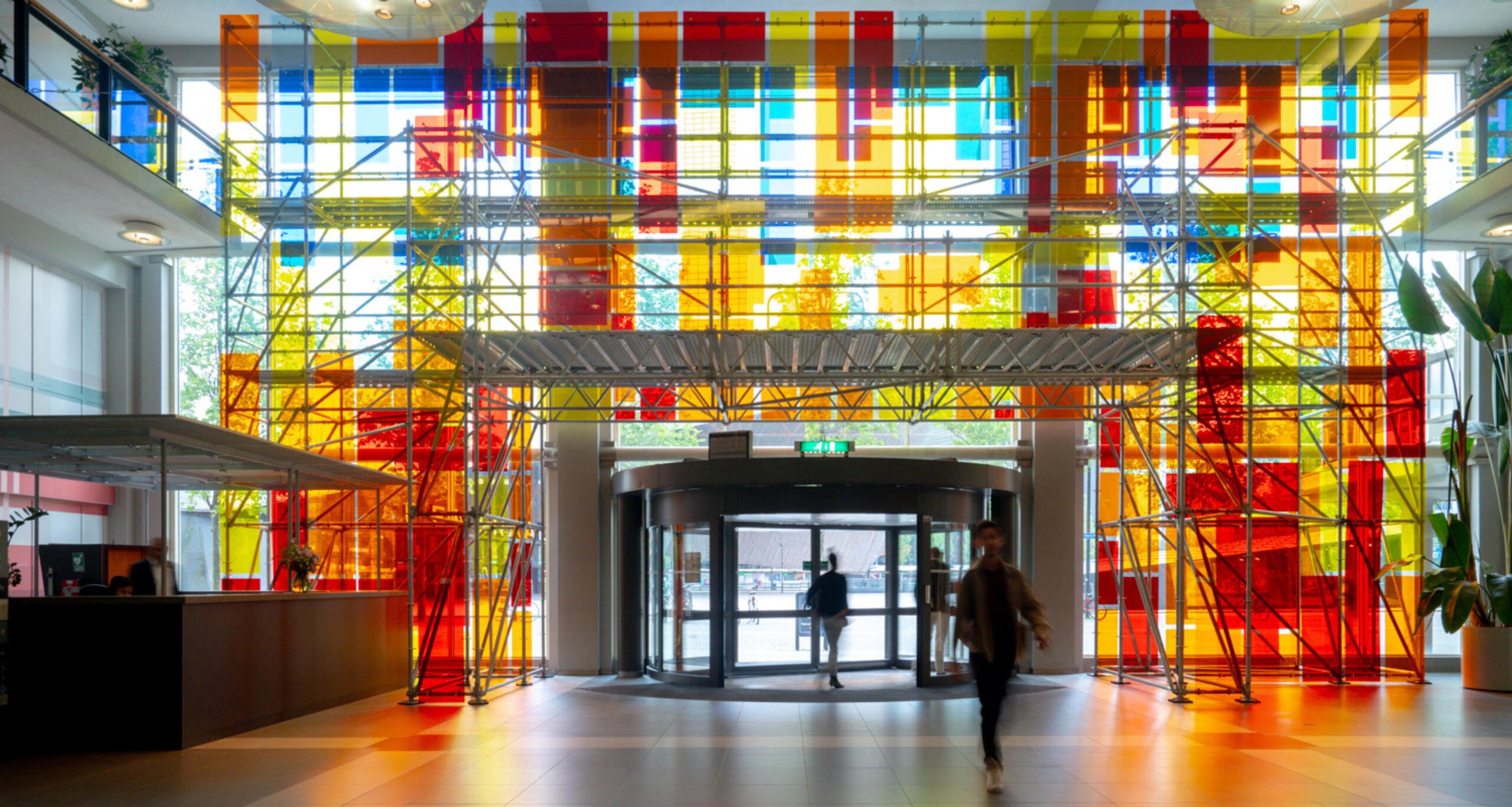 Inside Groot Handelsgebouw's lobby with light shining through multicolored glass windowpanes