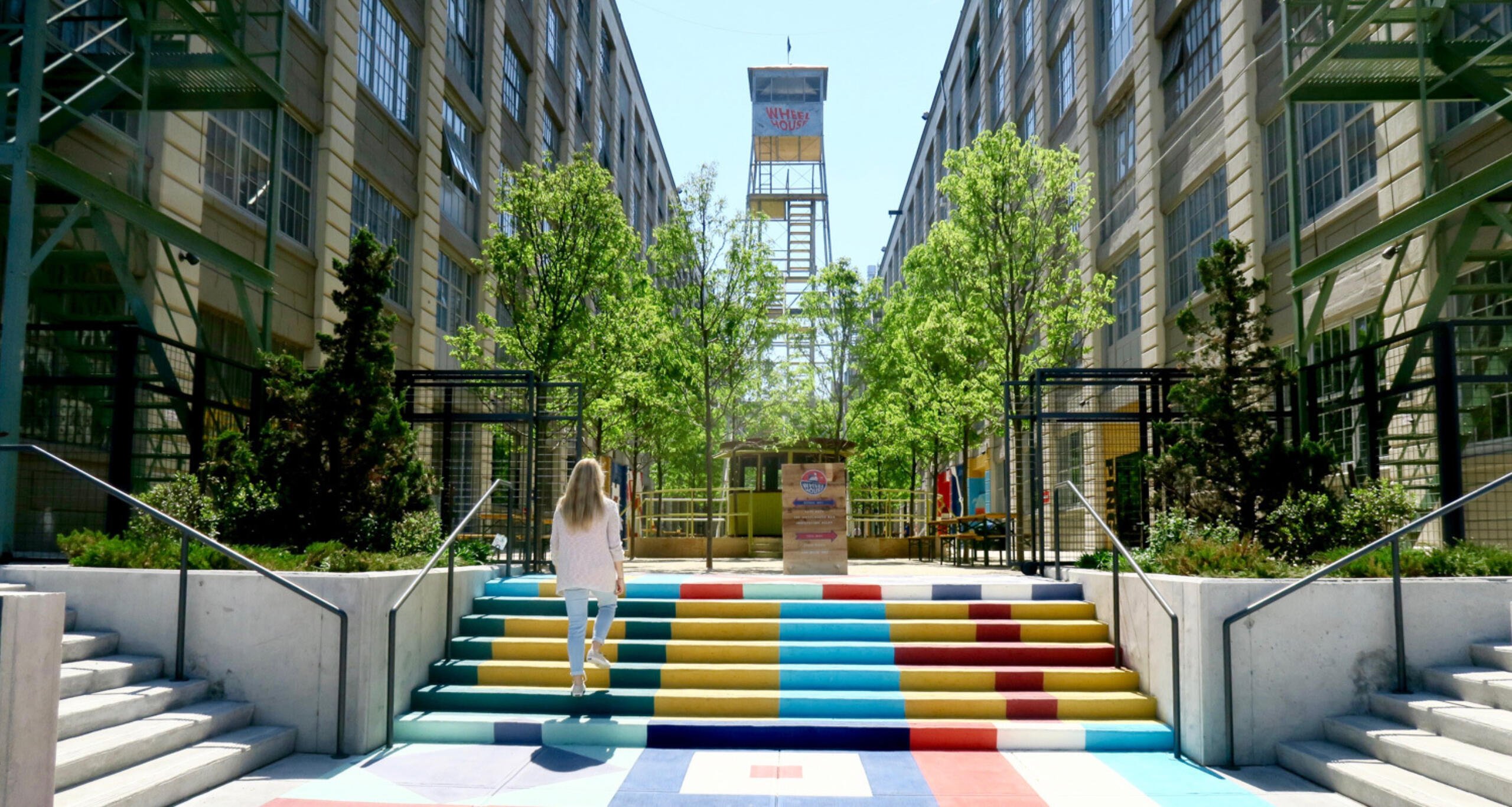 Outdoor courtyard between two buildings at Industry City with visitor walking up multicolored stairs