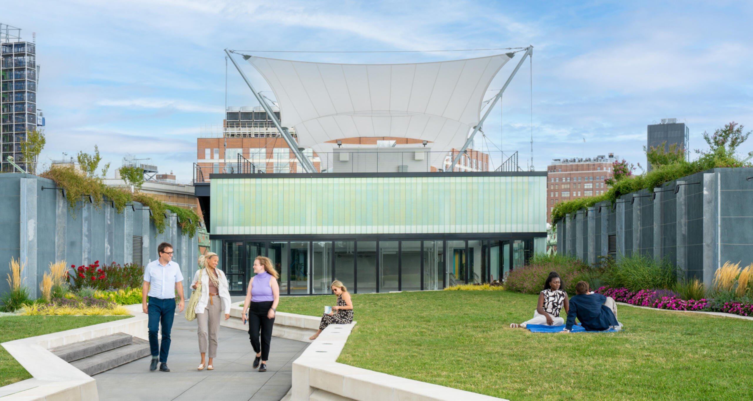 Pier 57 rooftop green space with visitors walking on path and sitting on lawn