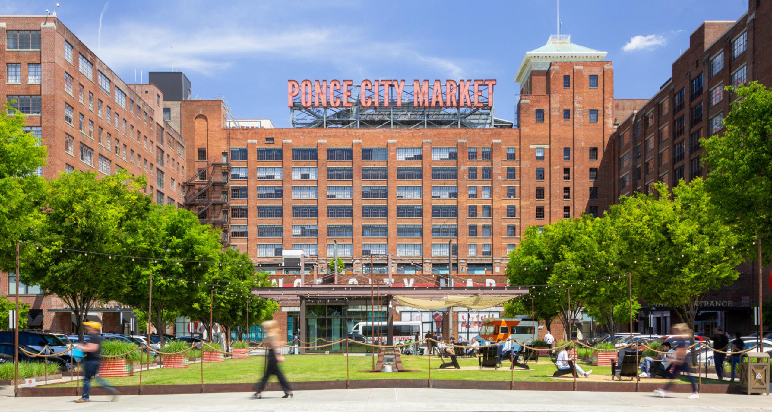 Visitors walking on a sidewalk in front of Ponce City Market's massive façade.