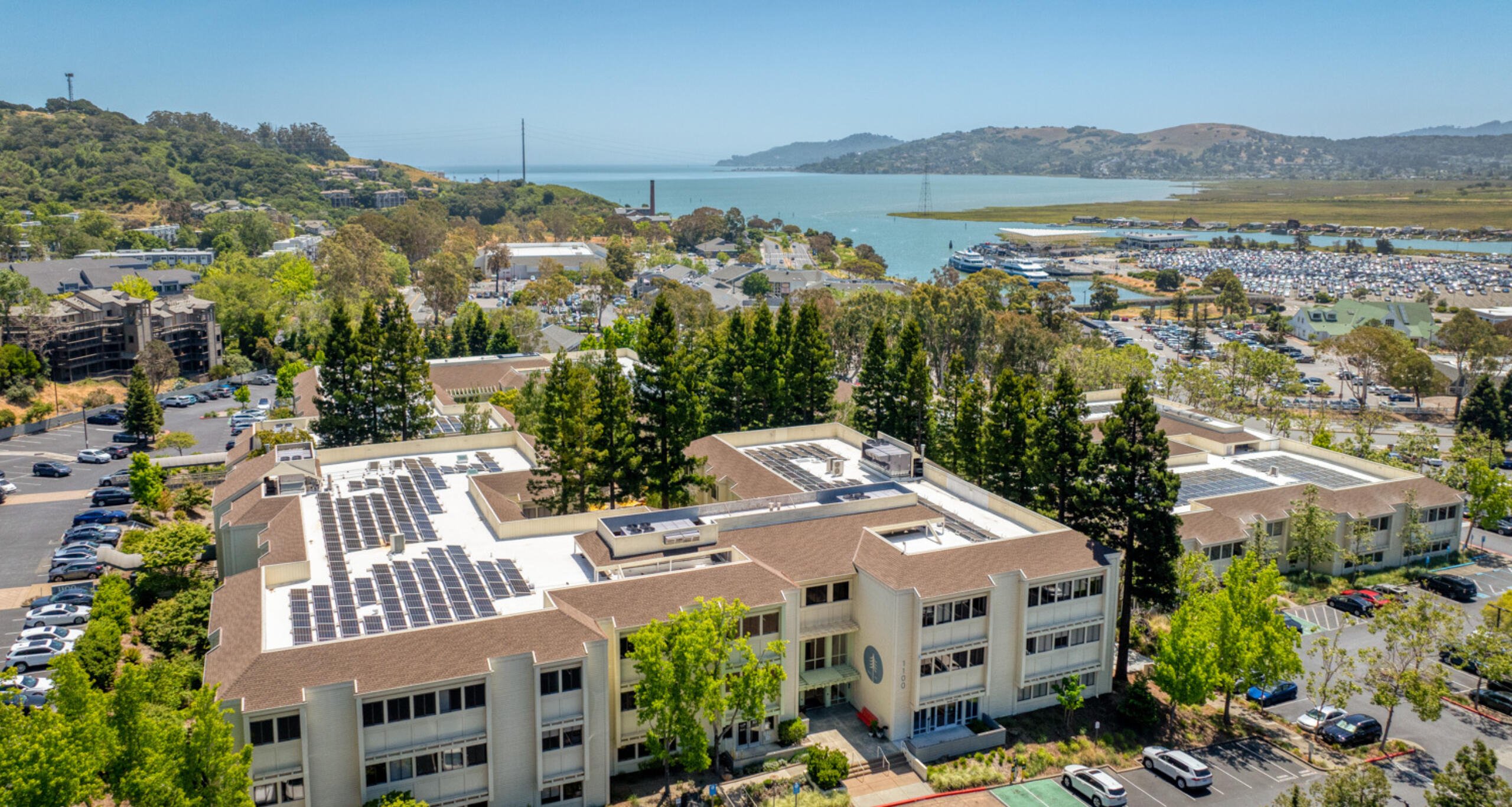 Ariel view of The Exchange at Larkspur Landing's rooftop solar panels with the San Francisco Bay in the background